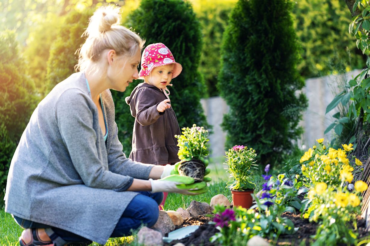 Moeder en dochter planten zomerbloeiers in de tuin. Foto: Adobe Stock / ronstik