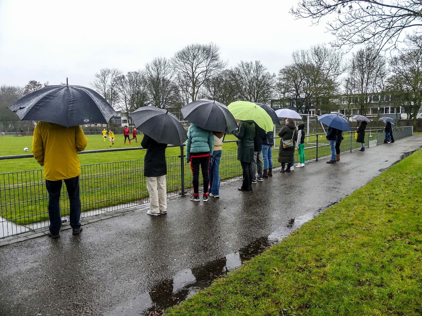 Zondagochtend komt de paraplu naast het sportveld goed van pas. Foto: Bart Brasser