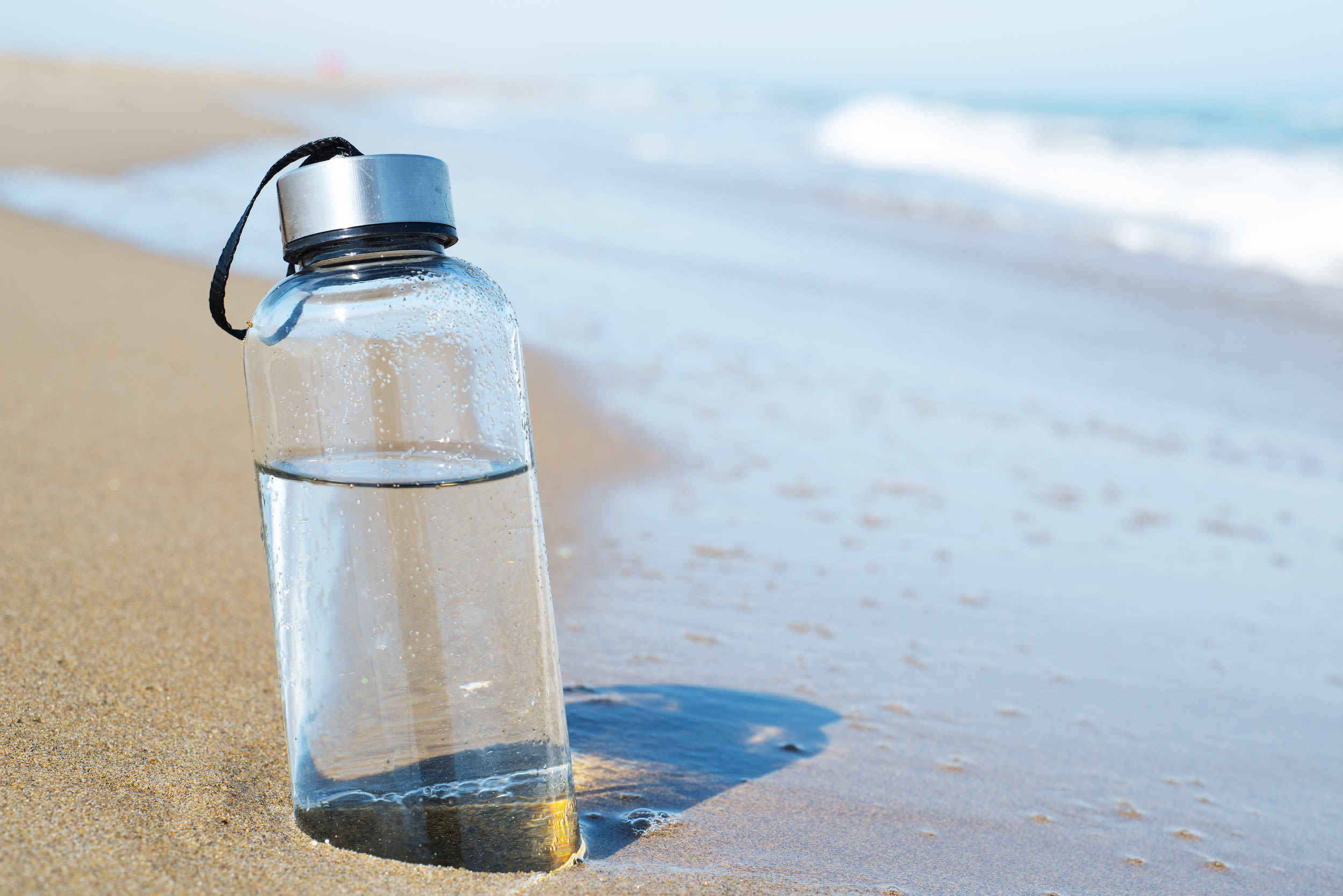 Met een herbruikbaar flesje blijft je gehydrateerd en laat je geen afval achter op het strand. Foto: Adobe Stock / nito.