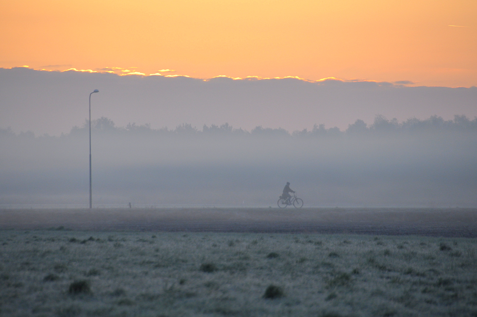 Fietser in een koude ochtend met mist, nevel en opkomende zon. Foto: Ben Saanen
