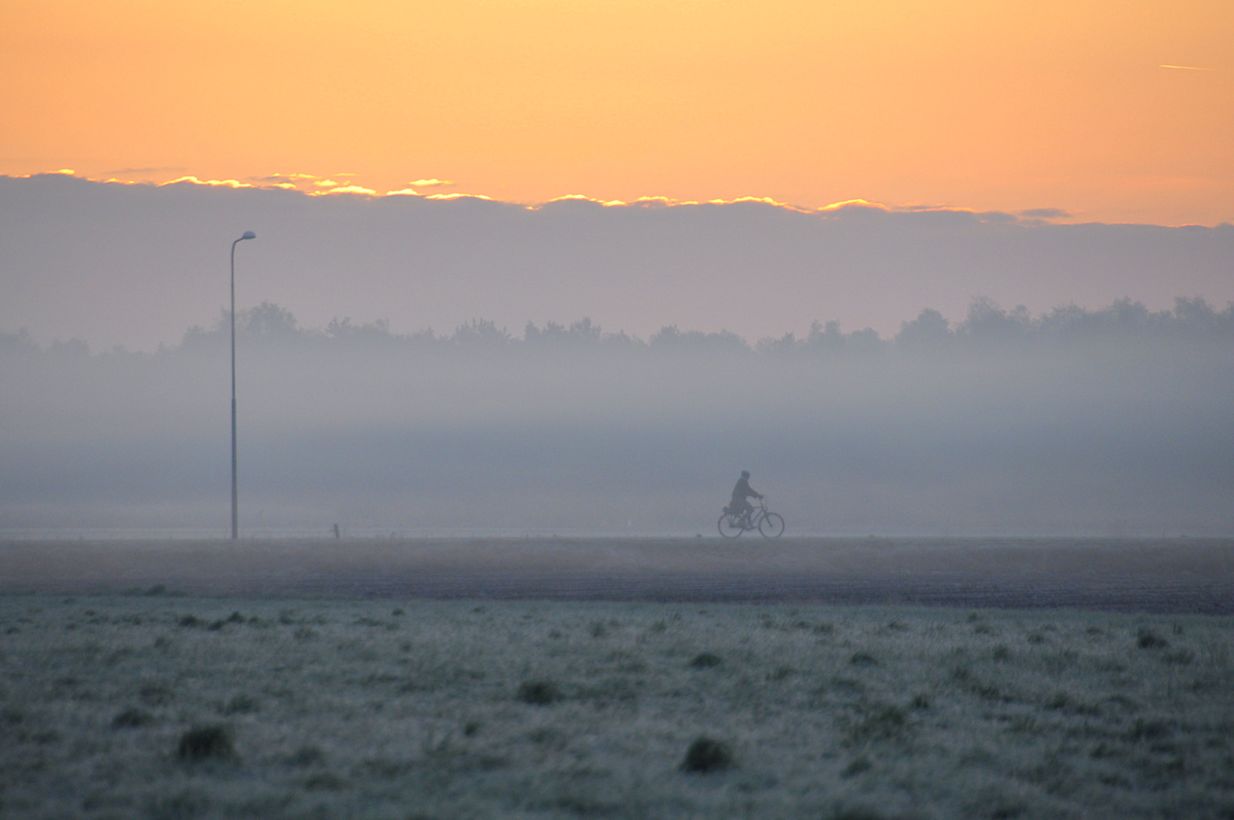 Fietser in een koude ochtend met mist, nevel en opkomende zon. Foto: Ben Saanen