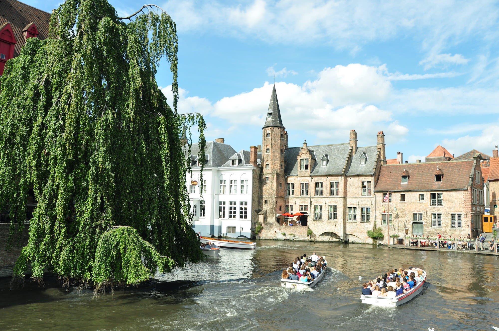 Toeristen in boten op de gracht in Brugge België. Foto: AdobeStock