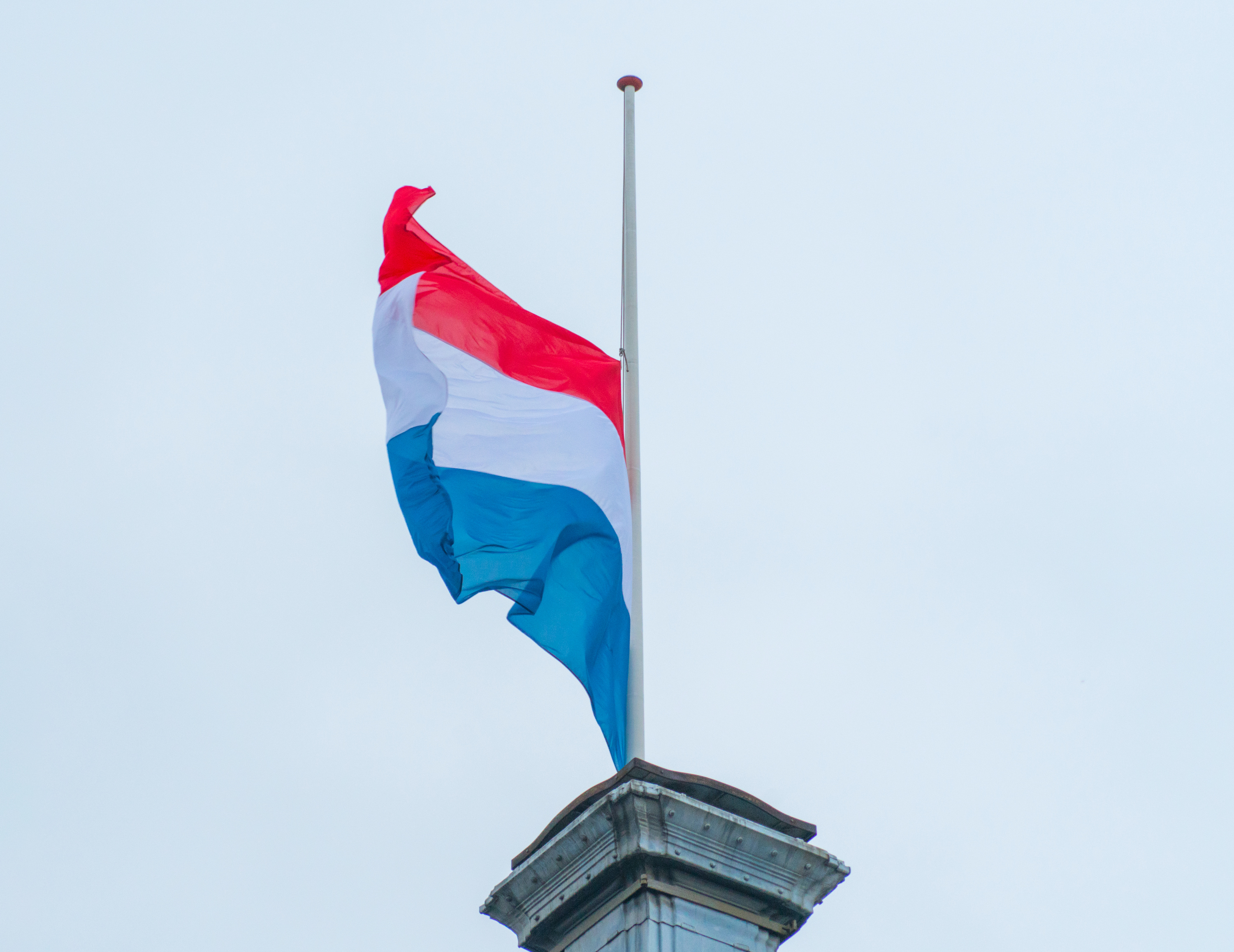 Vlag hangt halfstok tijdens bewolkte Dodenherdenking