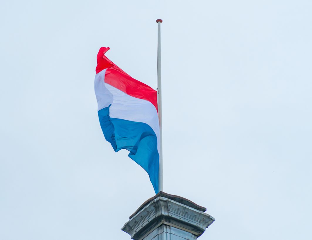 Vlag hangt halfstok tijdens bewolkte Dodenherdenking