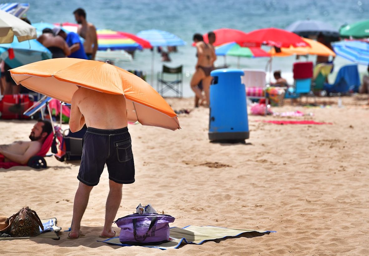 Zonaanbidders zoeken verkoeling op het strand in Benidorm. Foto: Robin Utrecht.