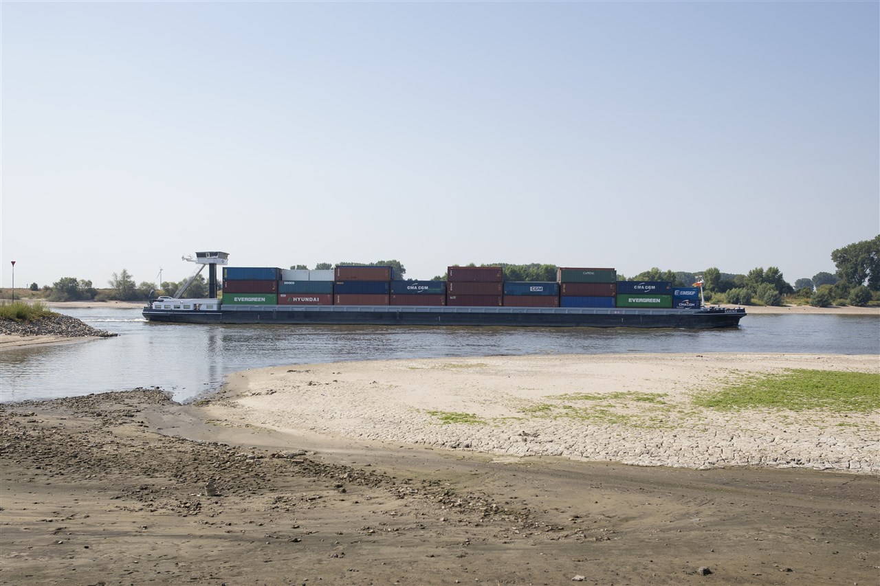 Schip vaart langs uitgedroogde oever van de Rijn. Foto: ANP JASPER JUINEN