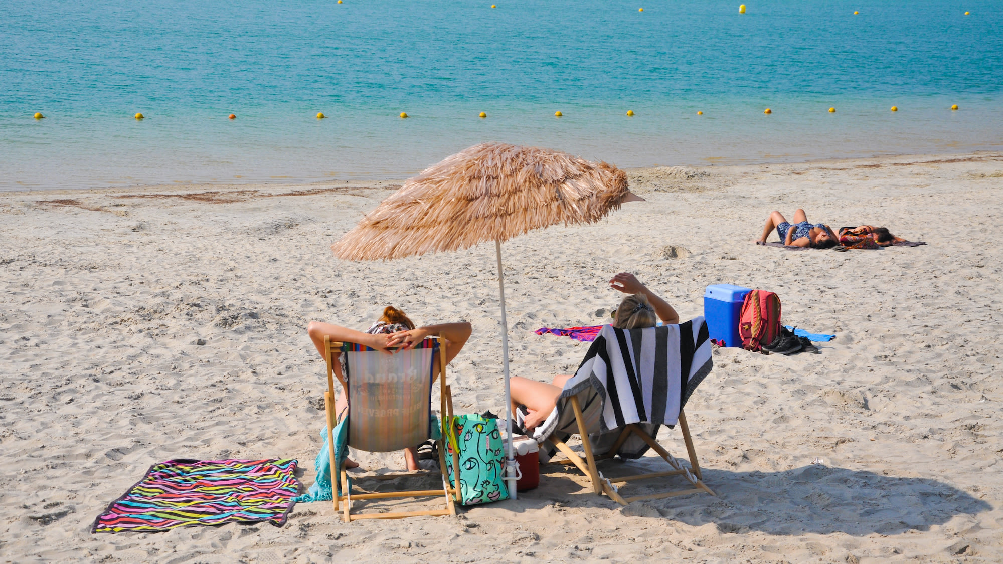 Twee vrouwen op strand in strandstoel met tropische parasol