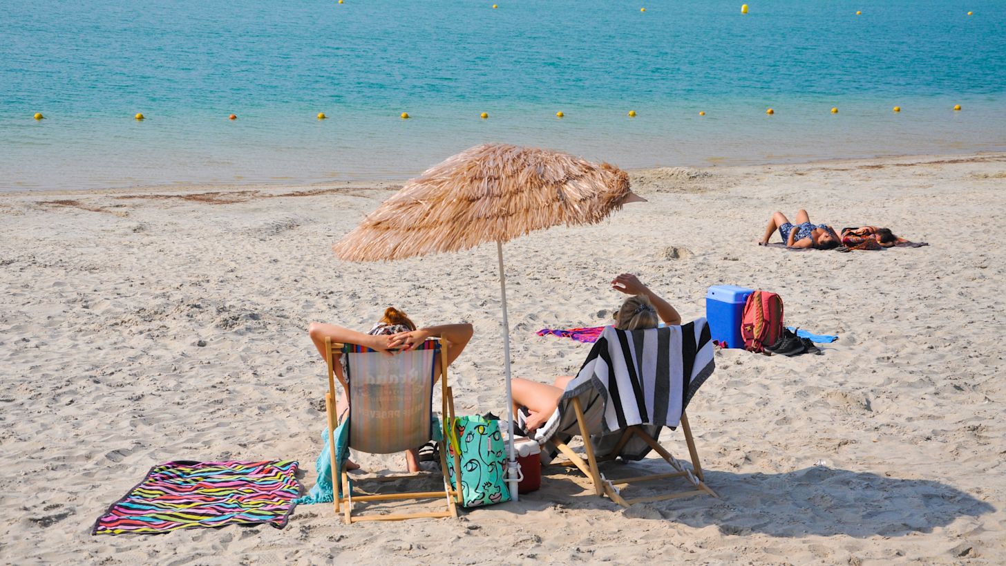 Twee vrouwen op strand in strandstoel met tropische parasol
