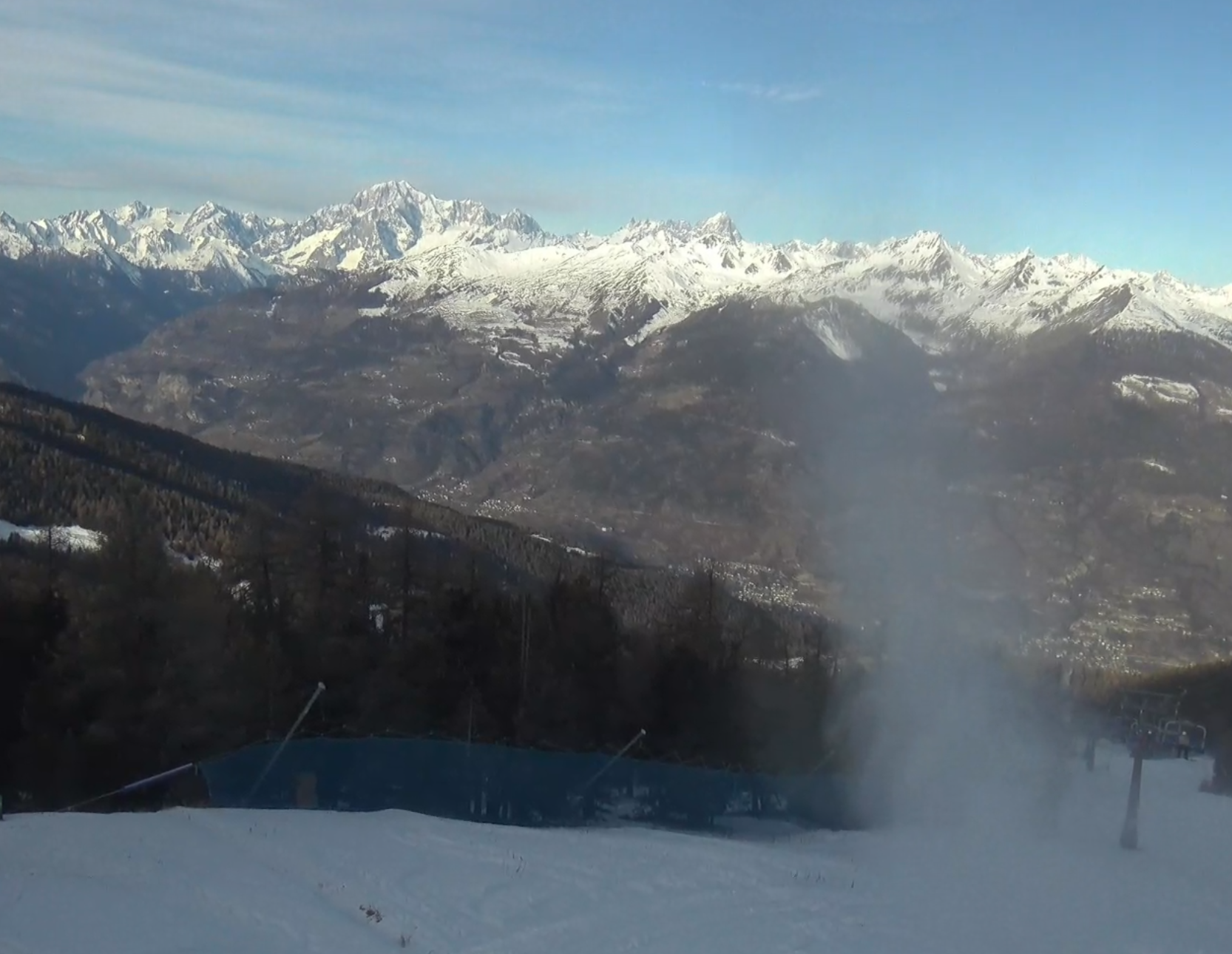 Een sneeuwkanon draait maandagochtend volop in het Italiaanse Pila - Chamolé Monte (2309 meter hoogte). De eerste wolkenvelden zijn op de achtergrond al te zien. Bron: Feratel