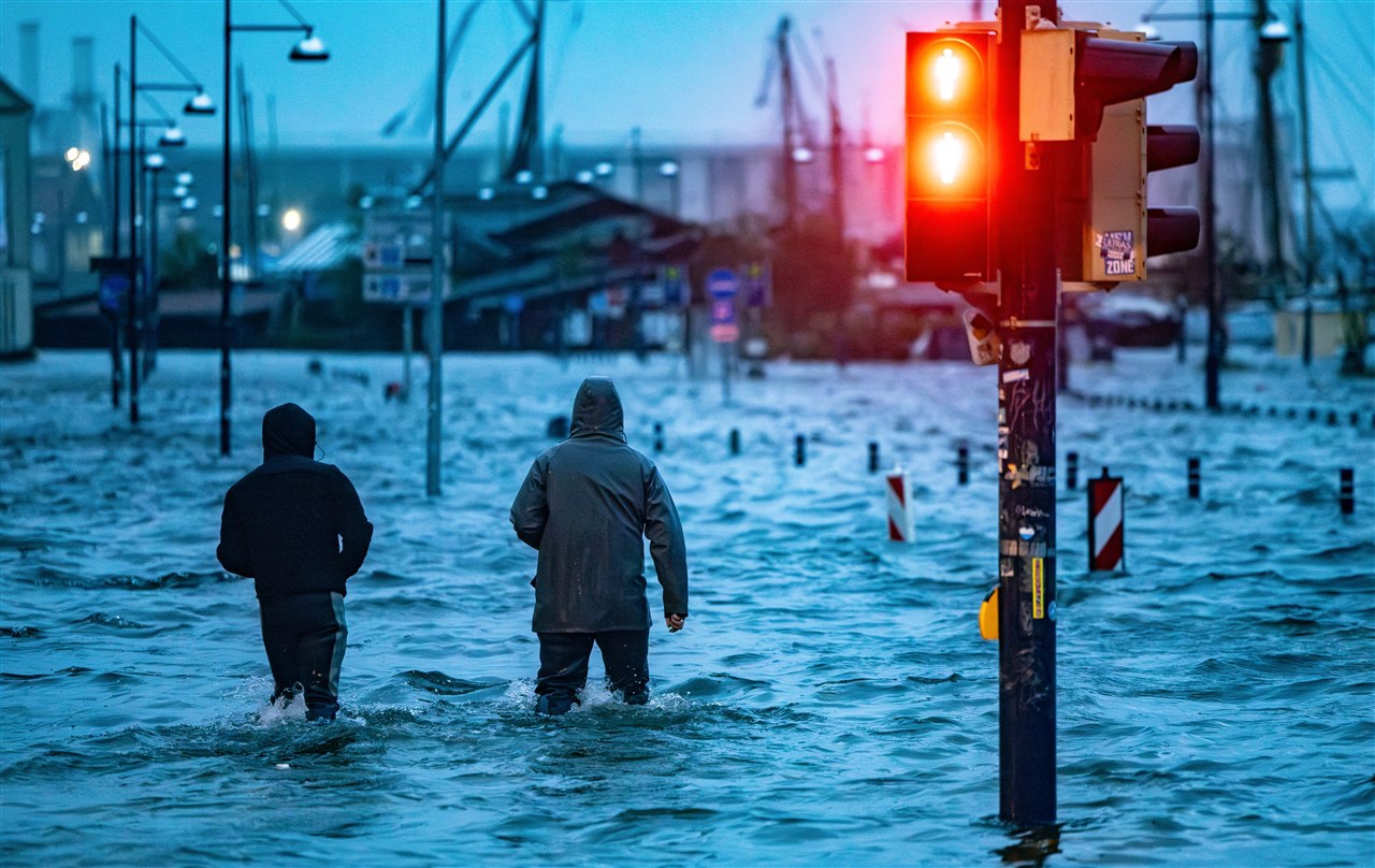 Mensen lopen door een ondergelopen straat in Flensburg. Foto: AFP / Axel Heimken