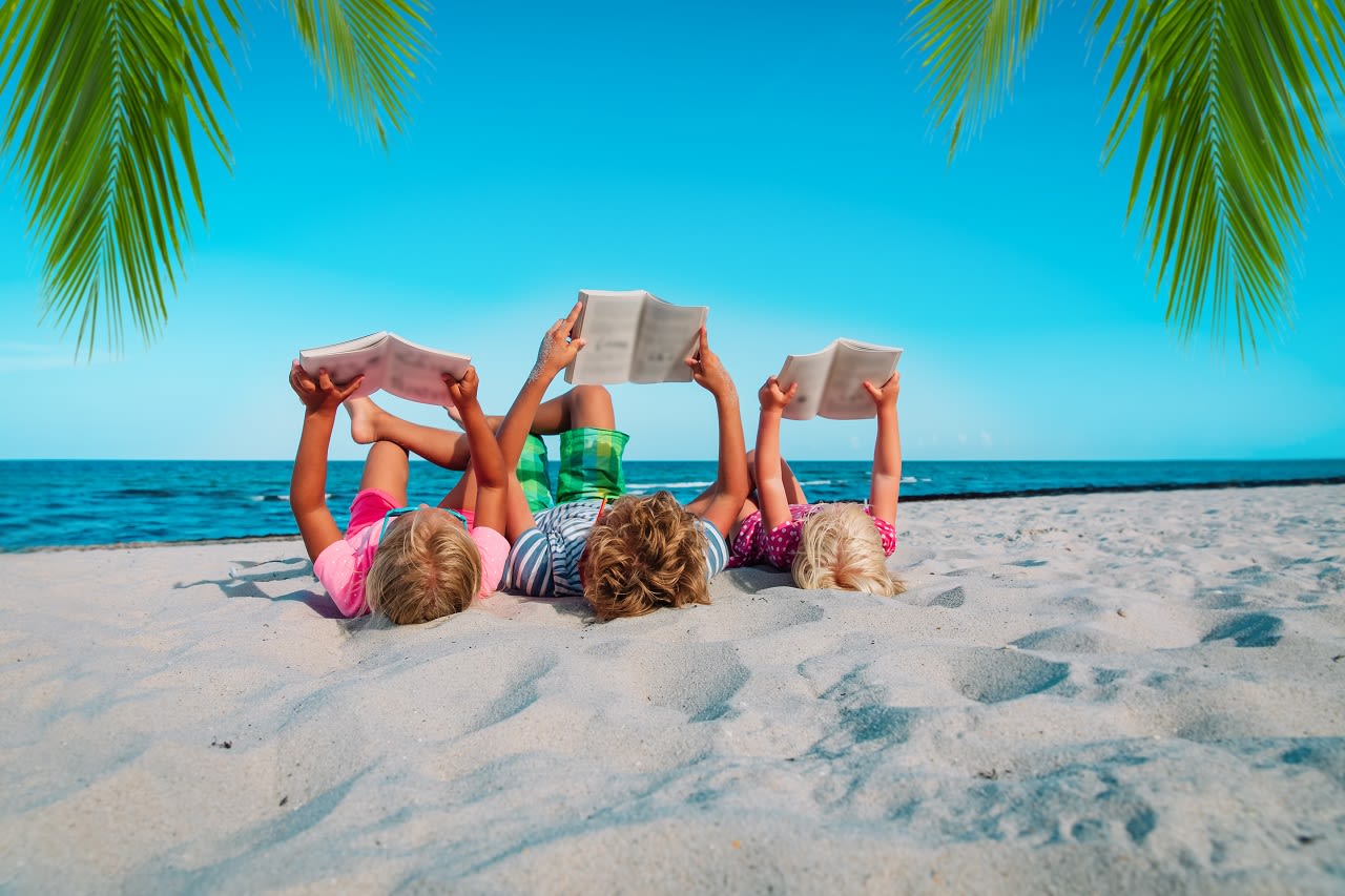 Kinderen lezen een boek op het strand. Foto: Adobe Stock / nadezhda1906
