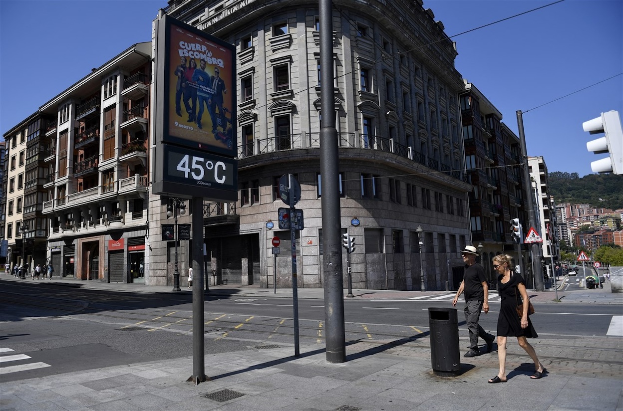 Een stel loopt langs een straatthermometer die 45 graden Celsius aangeeft. Foto: ANP / MASSIMO PERCOSSI.