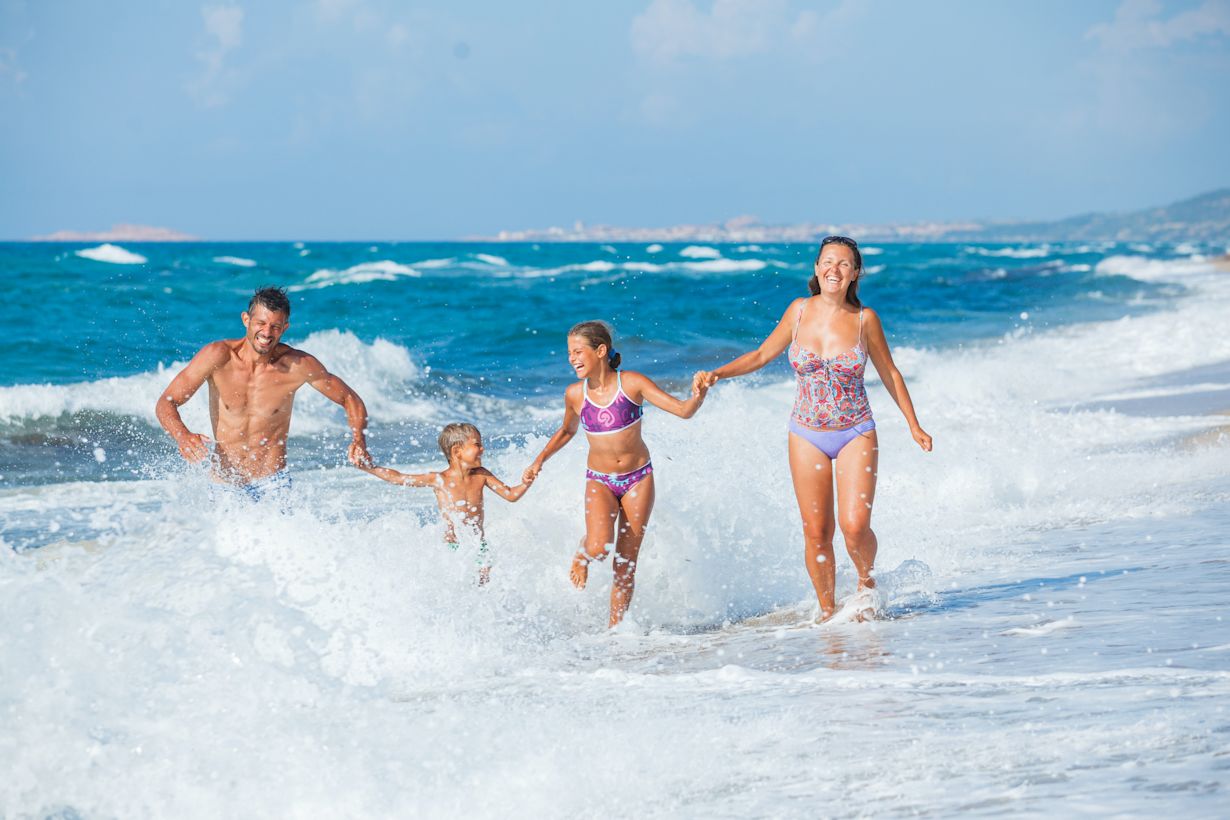 Familie met twee kinderen heeft plezier in de golven van de Middellandse Zee. Foto: Adobe Stock / Max Topchii