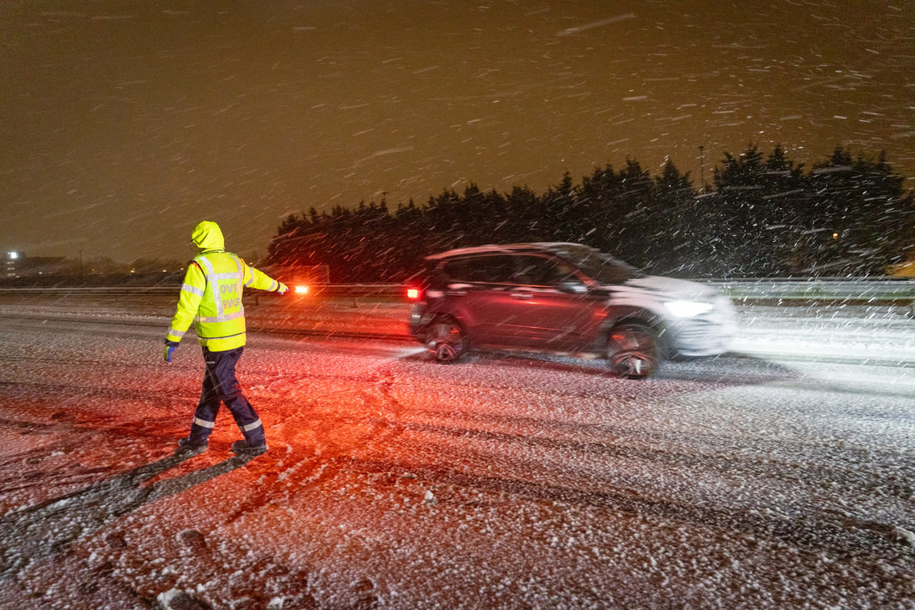 Een medewerker van Rijkswaterstaat maant automobilisten nadat een auto van de weg is gereden door gladheid in Grou op 9 januari. Foto: ANP / JARING RISPENS